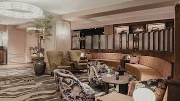 A modern lounge area with a sofa, armchairs, a round table, and a decorative mirror.