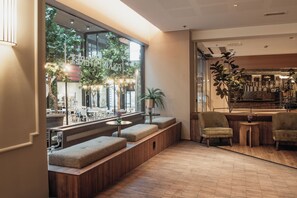 A modern interior with seating areas, a bar, and large windows. - Home Hotel Folketeateret (Oslo)