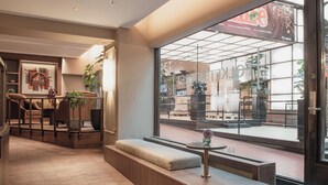 A modern hotel lobby with a seating area, a reception desk, and large windows overlooking the street. - Home Hotel Folketeateret (Oslo)