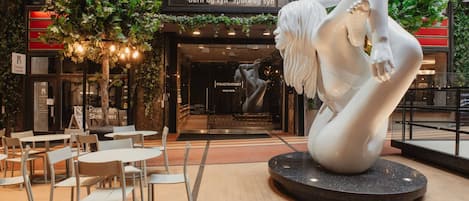 A modern indoor space with a sculpture, seating area, and a building entrance.