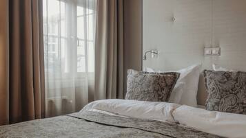 A hotel room with a bed, curtains, a headboard, and a window.