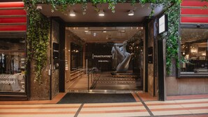 A hotel entrance with a glass door, a sign reading 'Folketeateret Home Hotel,' and a large sculpture in the center.