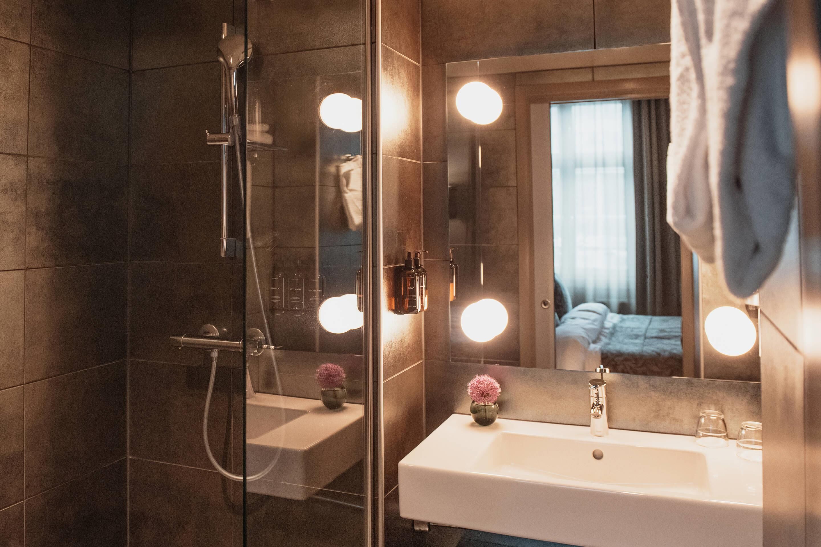 Une salle de bain moderne avec une douche à parois de verre, un lavabo blanc et un miroir avec éclairage intégré.