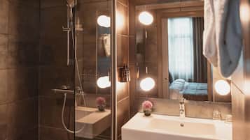 Une salle de bain moderne avec une douche à parois de verre, un lavabo blanc et un miroir avec éclairage intégré.