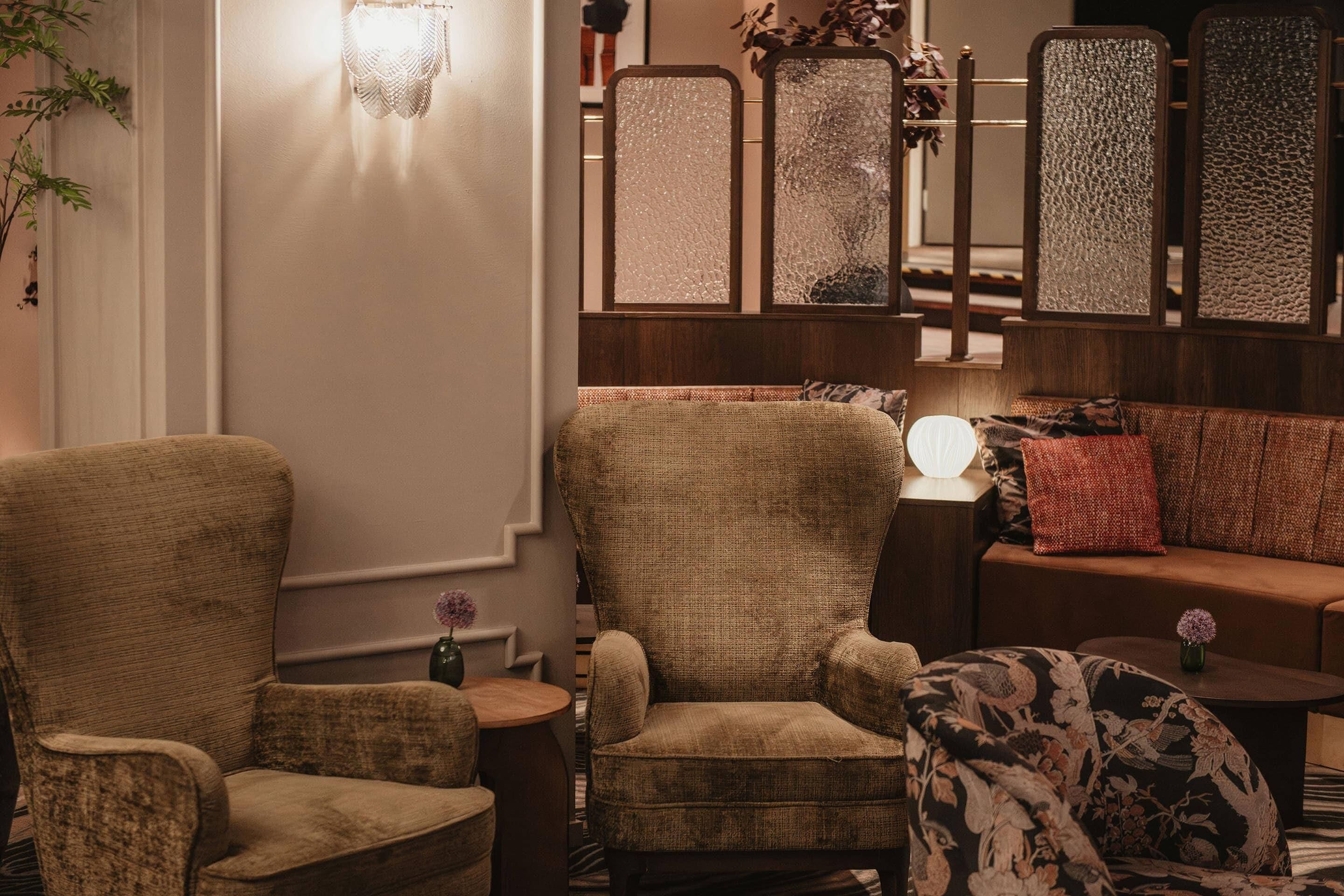 A cozy living room with a sofa, armchairs, and a decorative wall panel.