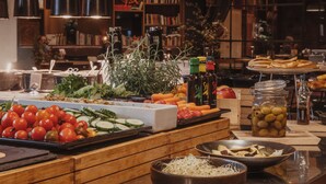 A buffet with various food items, a bookshelf, and hanging lights in a dining area. - Home Hotel Folketeateret (Oslo)