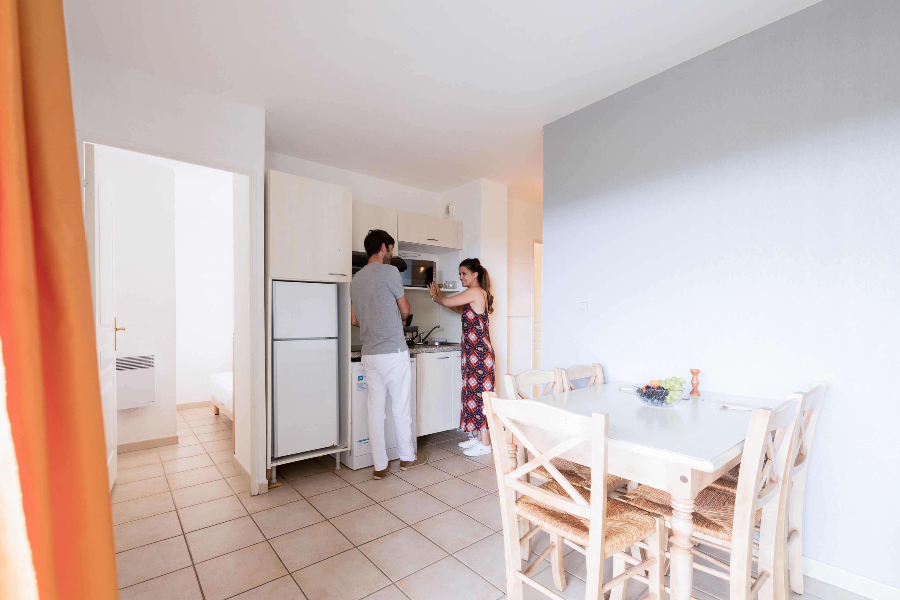 A modern kitchen with white cabinets and a dining area with a table and chairs.