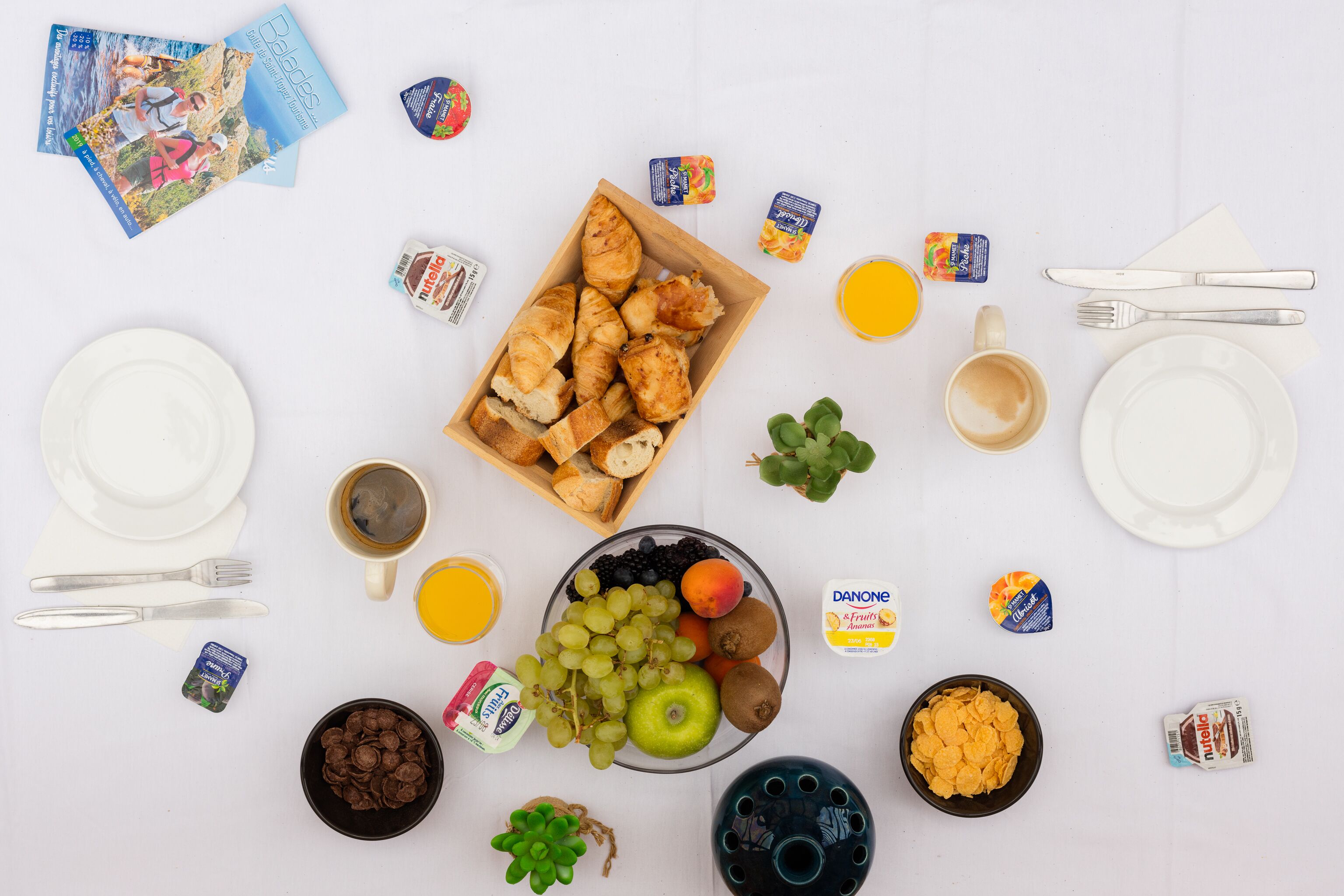 A breakfast setting with croissants, fruit, and beverages.