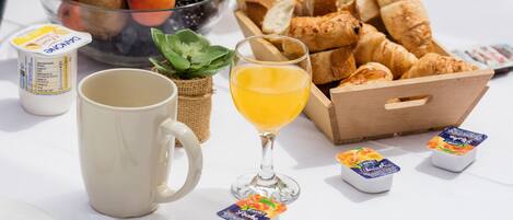 A breakfast setting with fruits, croissants, and beverages.