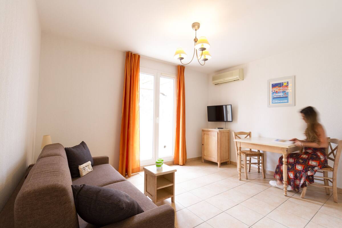 Un salon comprenant un canapé, une petite table, un téléviseur et un coin repas avec une chaise et une table.