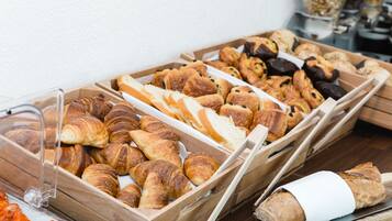 A variety of baked goods displayed in wooden trays, including croissants and bread.