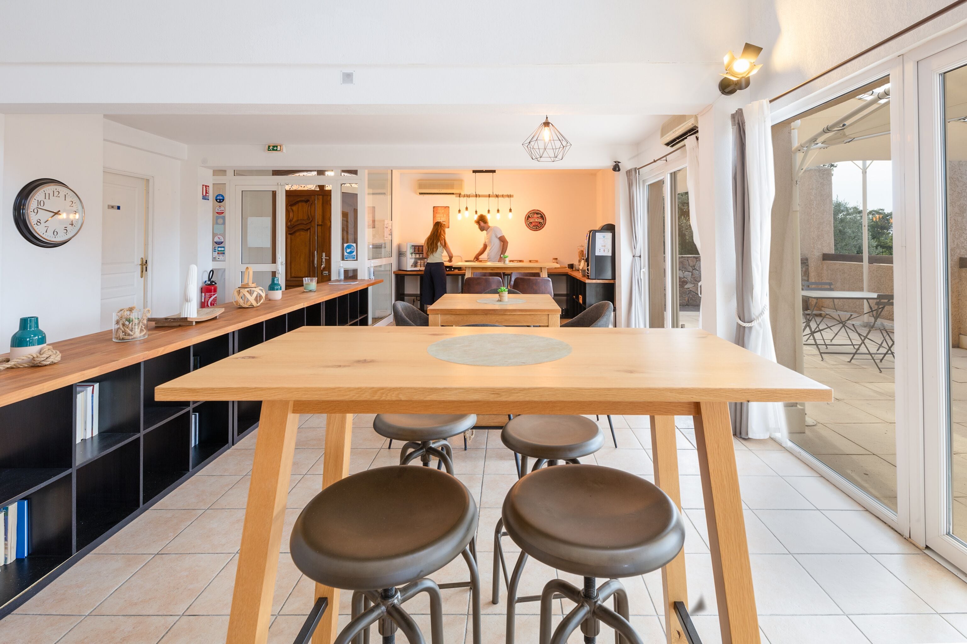 A modern kitchen with a central island, bar stools, and a large window.