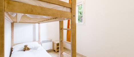 A bunk bed with a white mattress and a teddy bear on the lower bunk.