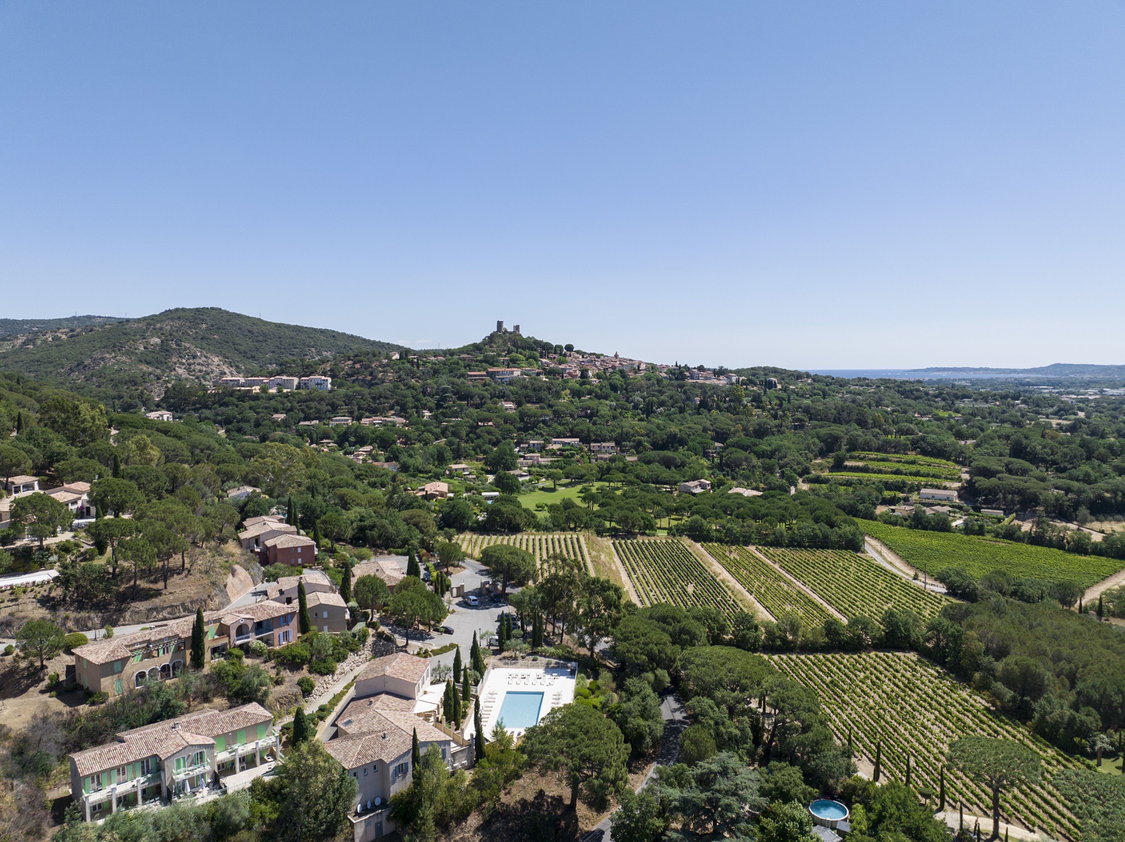 Un pueblo en la ladera con viñedos en terrazas, casas tradicionales y un castillo en la colina.