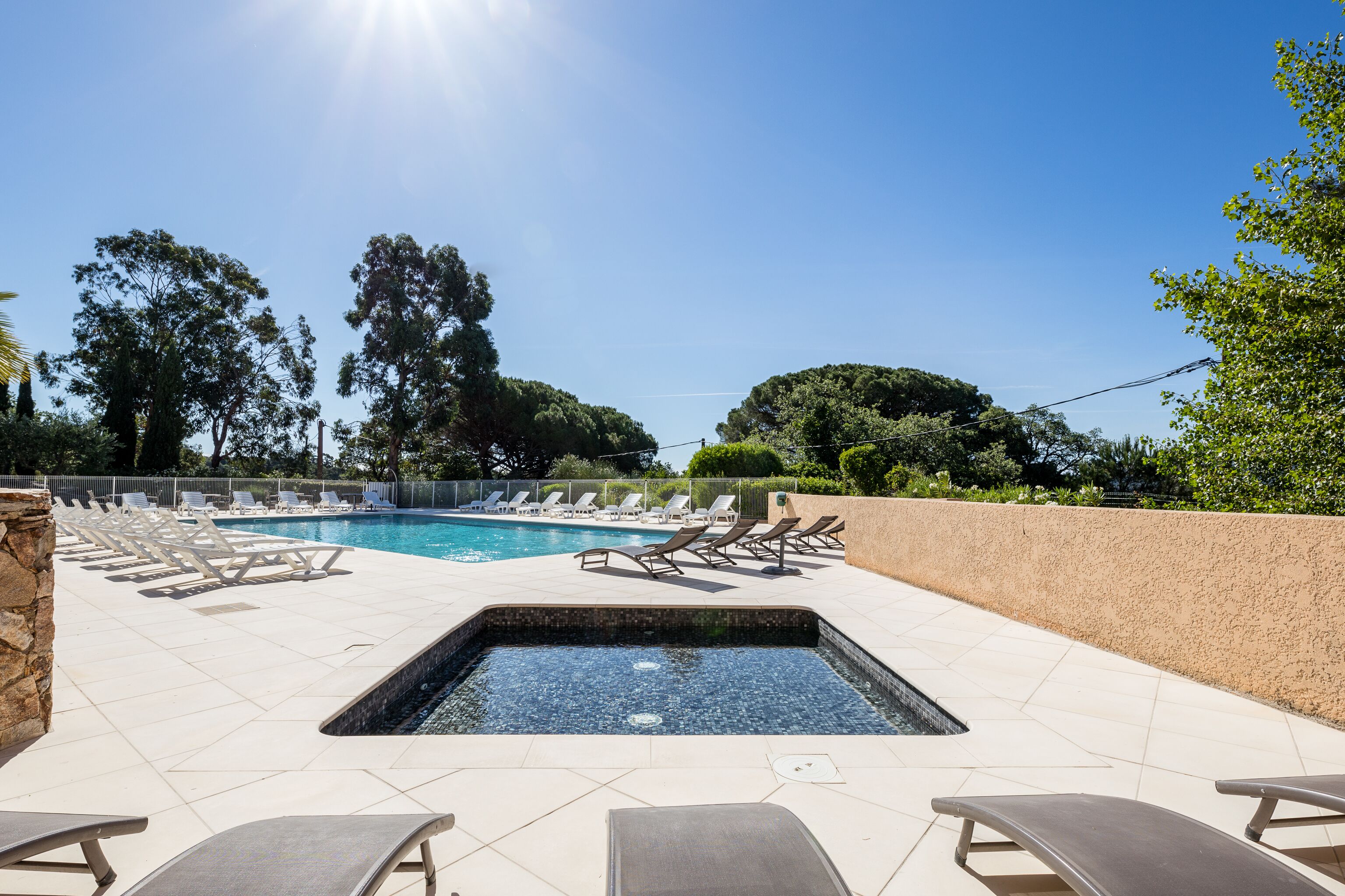 Una piscina con sillones de descanso y una pequeña zona de hidromasaje.