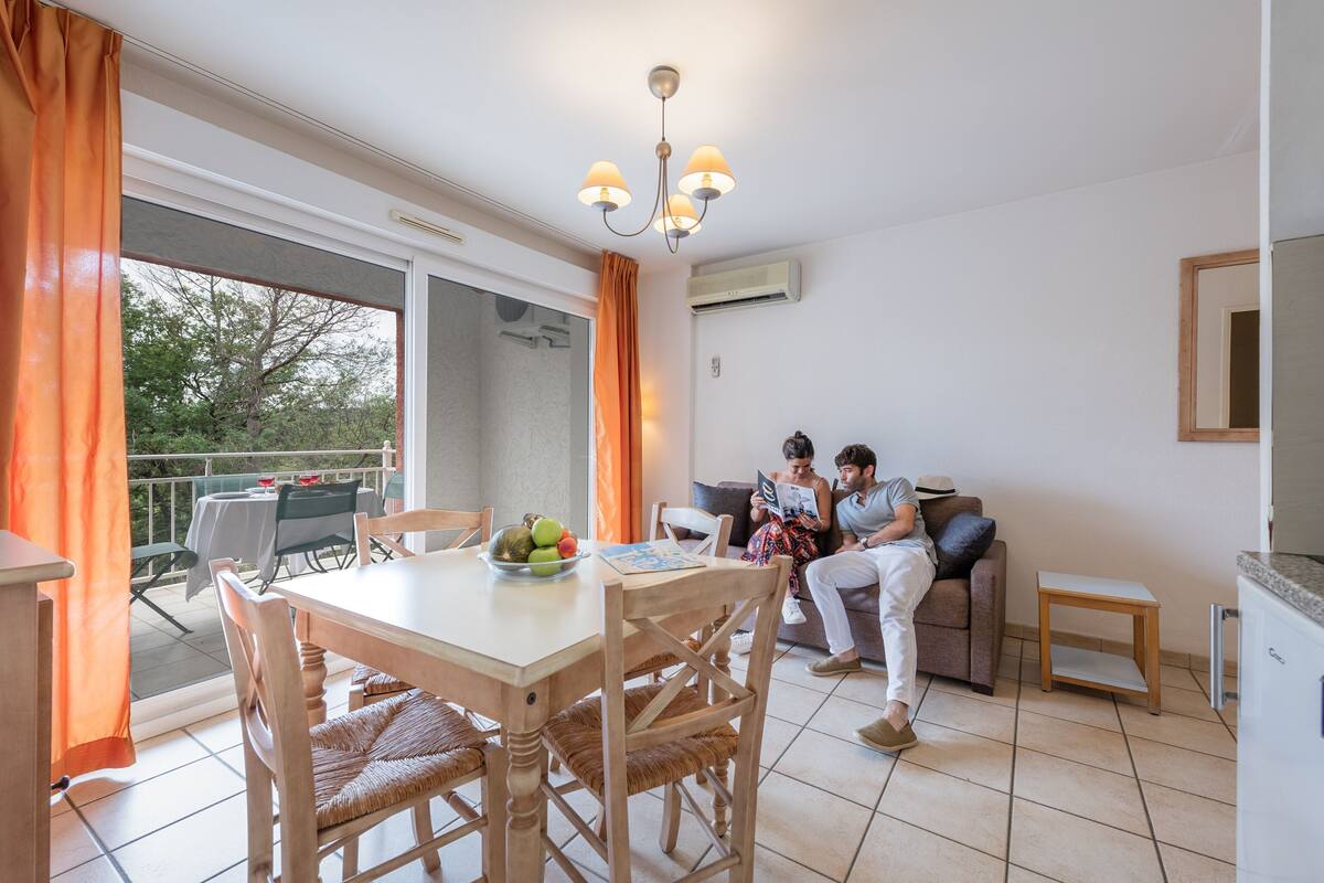 Un coin repas avec une table et des chaises, un balcon avec une table et des chaises, et un espace de vie avec un canapé et une petite table.