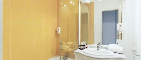 A bathroom with a glass-enclosed shower, a white sink, and a mirror.