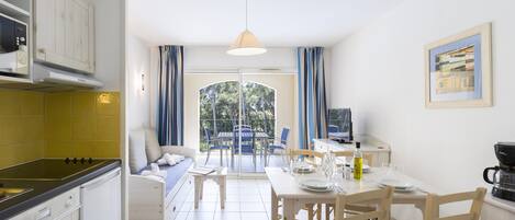 A modern kitchen with a dining area, a TV, and a view of the outdoors.