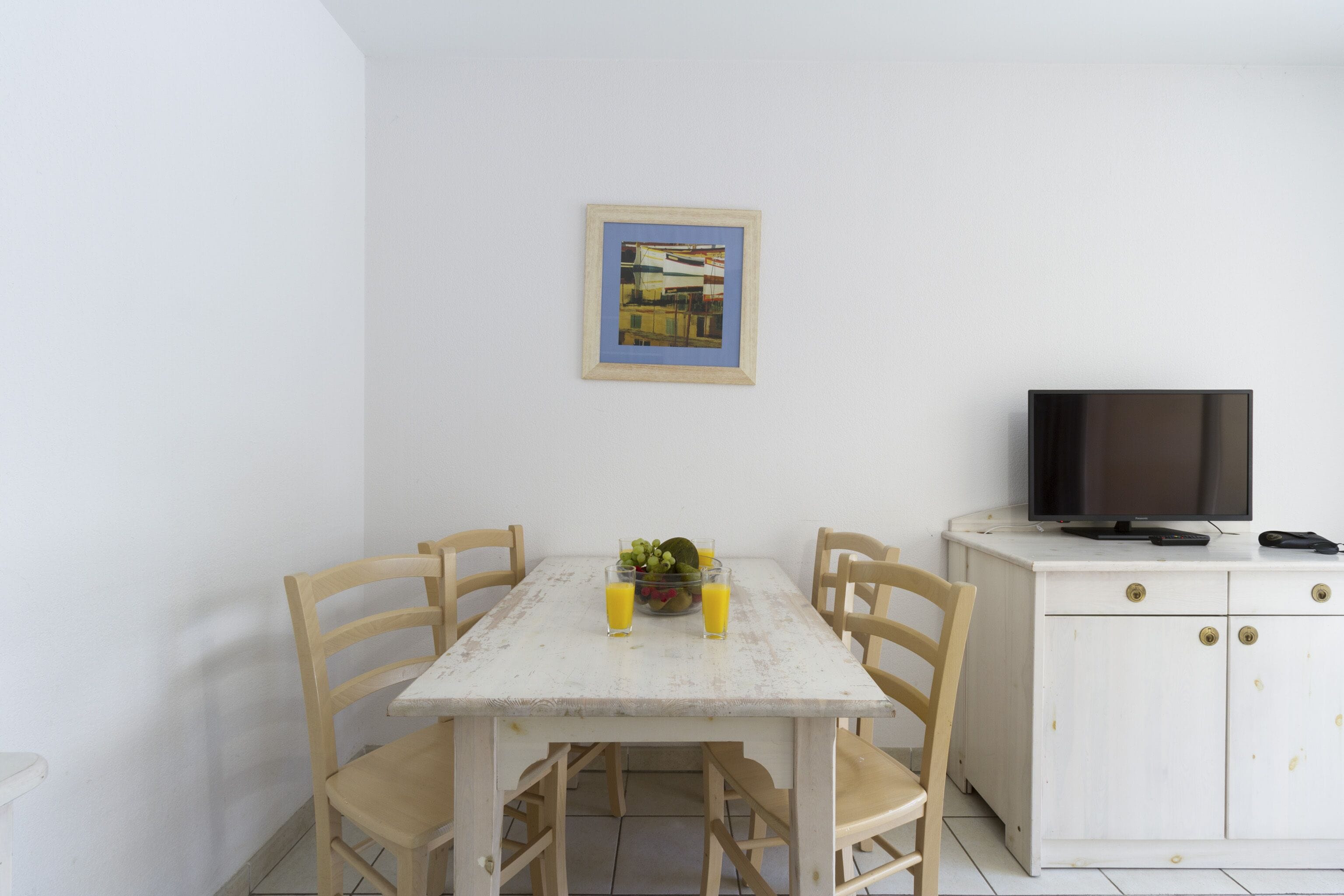 A dining area with a table, chairs, a television, and a cabinet.