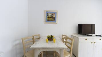 A dining area with a table, chairs, a television, and a cabinet.