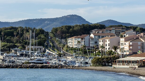 Marina con barcos, playa y edificios con balcones que dan al agua.