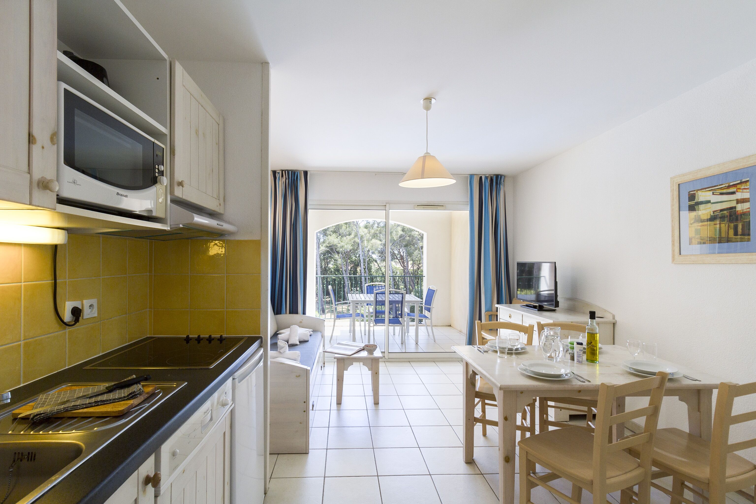 Une cuisine équipée d’un four à micro-ondes, d’une cuisinière et d’un coin repas avec des chaises et une table.