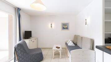 A modern, well-lit living room with a sofa, a small table, and a television on a cabinet.