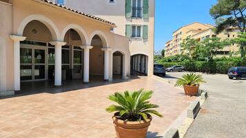 A building with a tiled entrance, multiple arches, and potted plants.