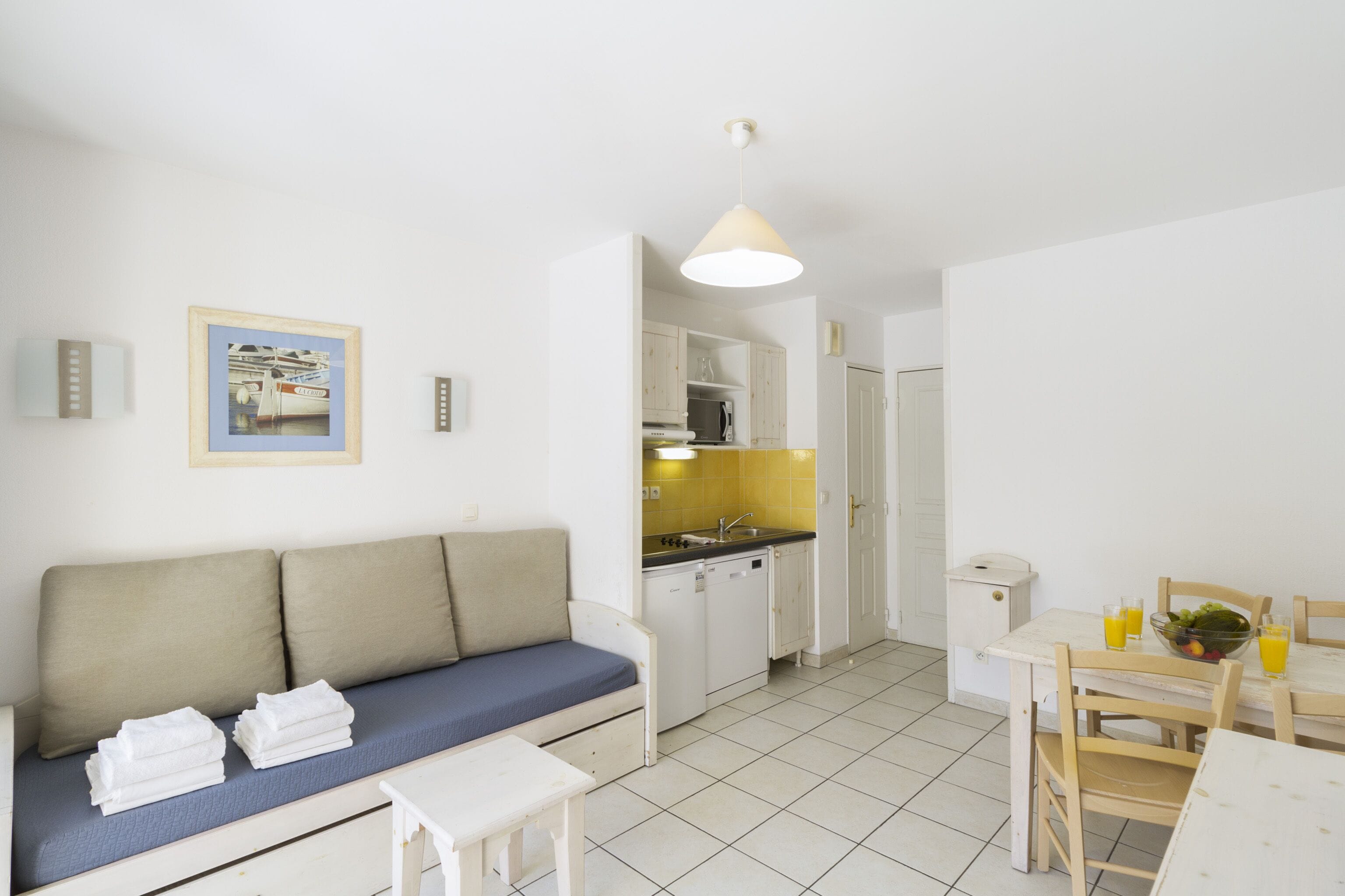 A compact living space with a sofa, a dining table, and a kitchen area.