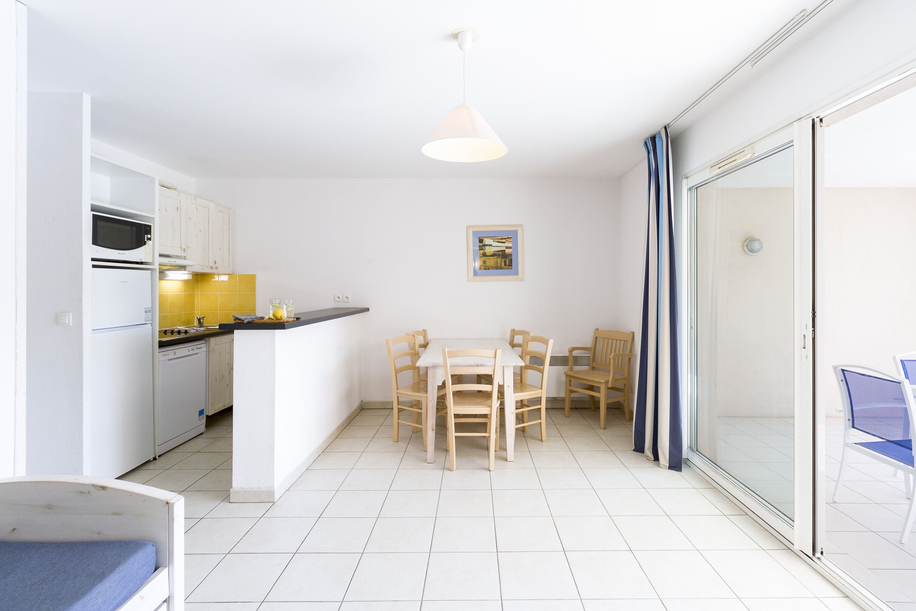 A compact kitchen with white cabinets, a microwave, and a small dining area with a table and chairs.
