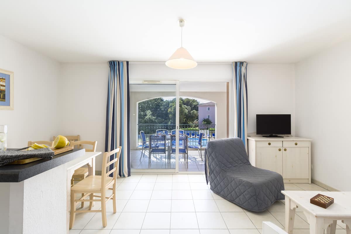 Una sala de estar moderna con un sofá, un televisor y un comedor con sillas y una mesa.