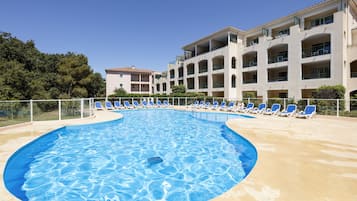 Una piscina al aire libre de temporada, sombrillas, tumbonas
