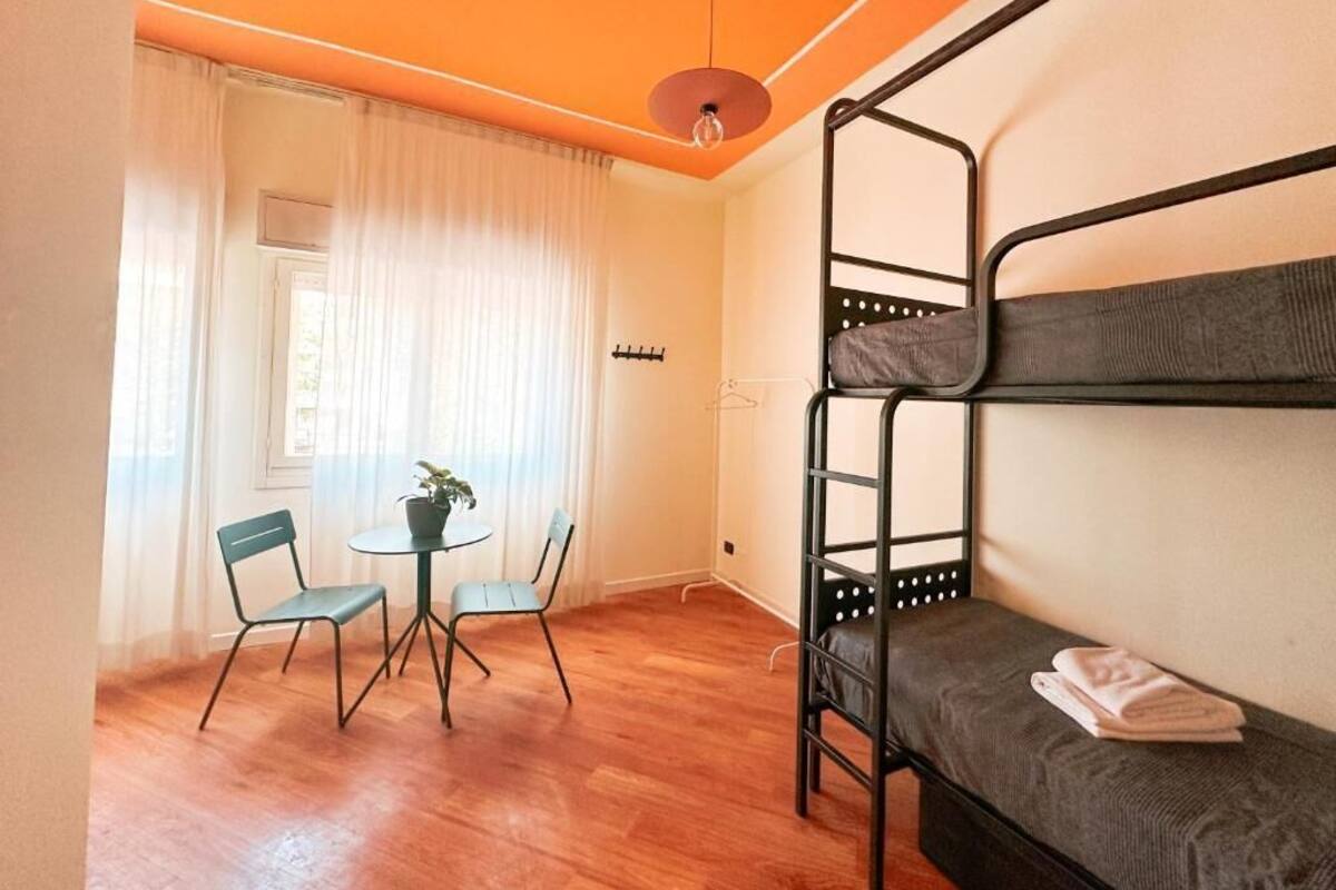 A room with a bunk bed, a small table with chairs, and a potted plant.