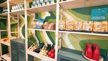 Botiga d'alimentació amb prestatges plens de pasta, aliments en conserva i fruites i verdures fresques.