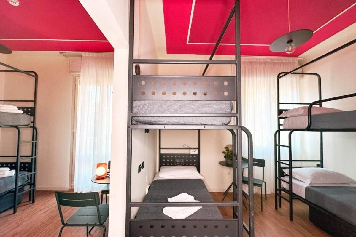 A dormitory room with bunk beds, a desk, and a chair.