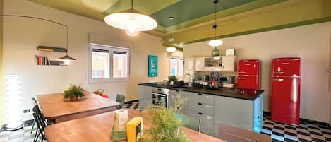 Una cocina con una mesa de madera, electrodomésticos rojos y suelo de cuadros.