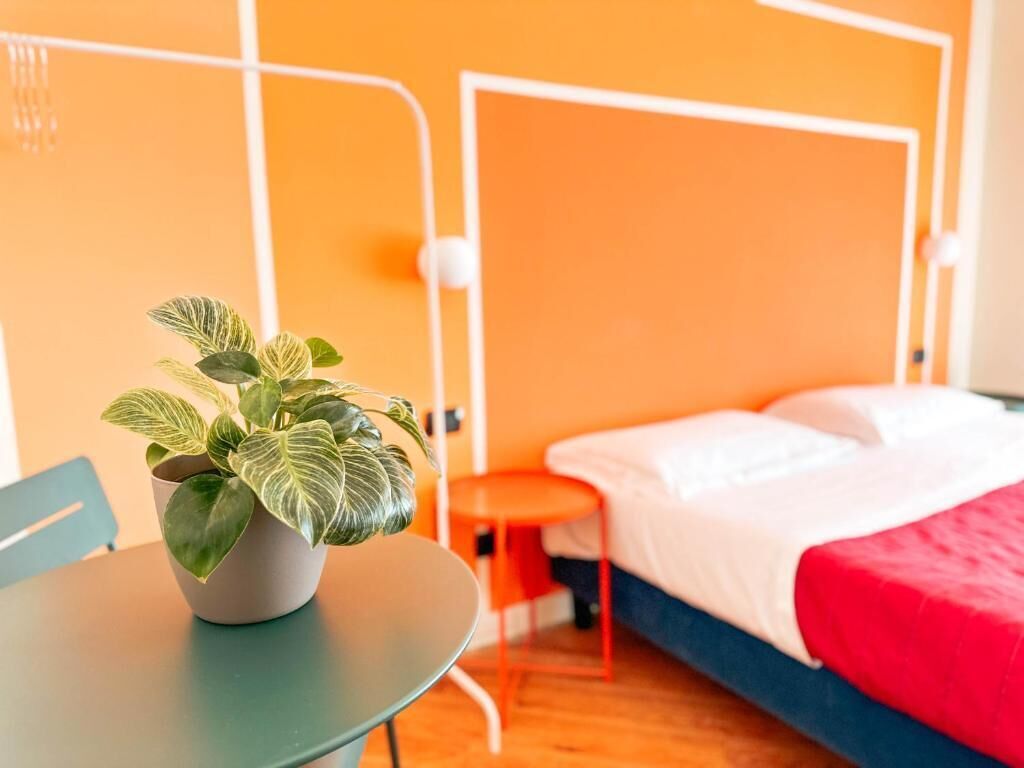 Een hotelkamer met een bed, een kleintje tafeltje met een plant en een stoel.
