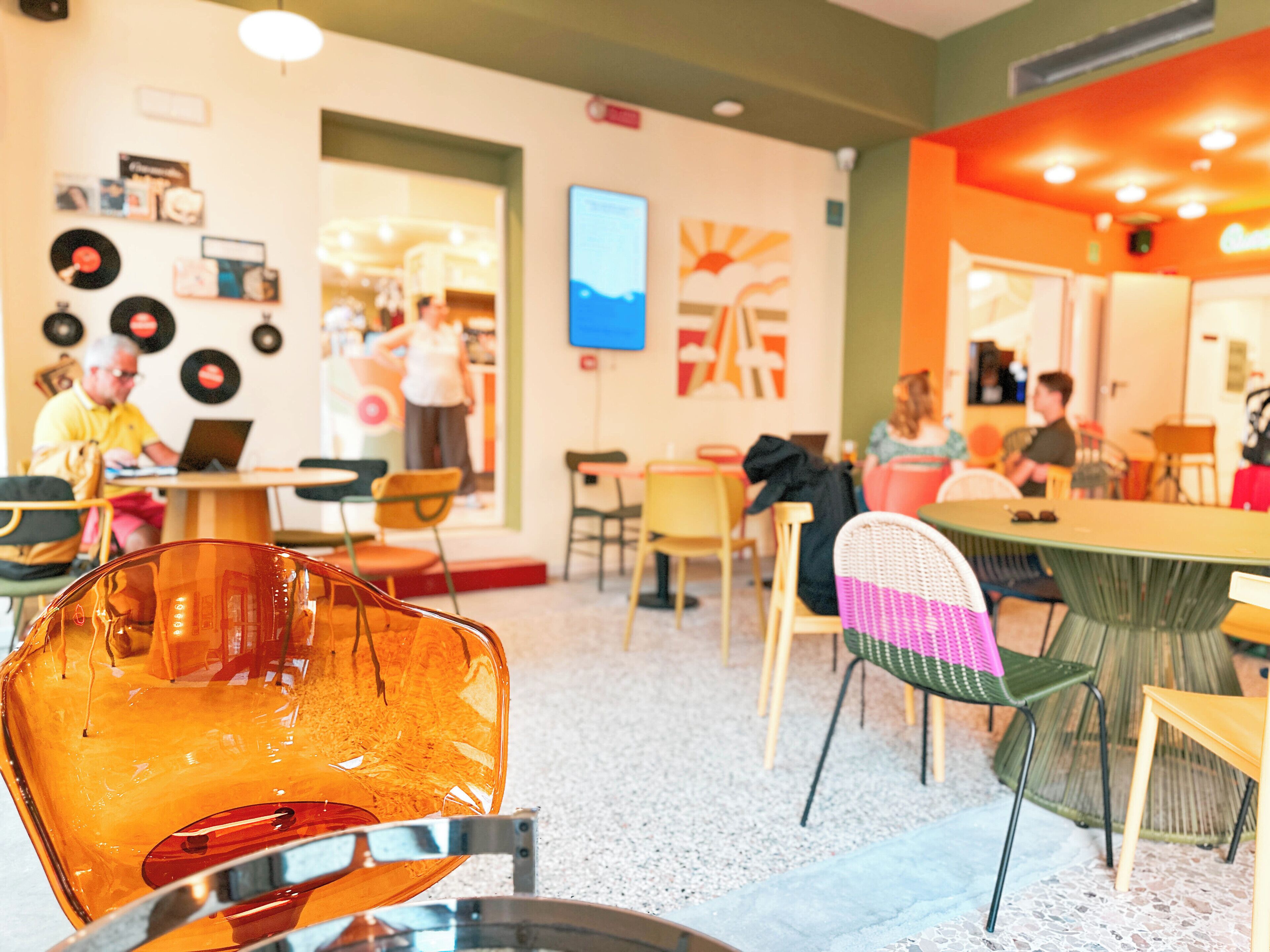 Un café avec des tables et des chaises, un mur décoré de disques et un écran de télévision.