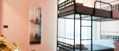 Habitación con literas, una planta sobre una mesa y un cuadro en la pared.