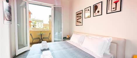 A hotel room with a bed, a balcony, and a view of buildings outside.