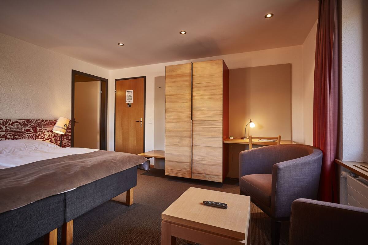 Una habitación de hotel con cama, escritorio, silla y armario.