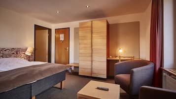 Una habitación de hotel con cama, escritorio, silla y armario.