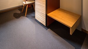 Une pièce avec un plafond en bois, un bureau avec une chaise, un petit banc et une fenêtre avec des rideaux.