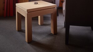 Une cabane aux murs en bois, une fenêtre donnant sur des montagnes enneigées, une petite table et deux chaises.