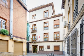 A multi-story building with balconies, a green awning, and a sign indicating a restaurant. - Hotel Boutique Reina Mora (Granada)