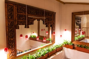 A bathroom with a large mirror, wooden paneling, and potted plants. - Hotel Boutique Reina Mora (Granada)