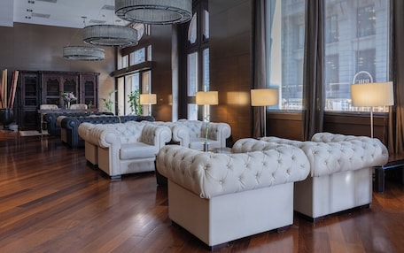 A spacious lobby with a large seating area, a grand piano, and a large window with curtains.
