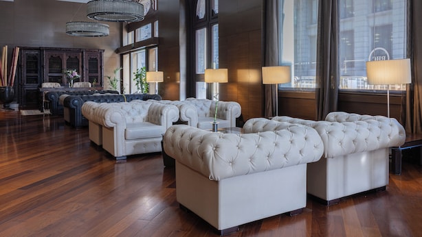 A spacious lobby with a large seating area, a grand piano, and a large window with curtains.