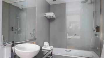 A modern bathroom with a large white sink, a mirror, a glass-enclosed shower, and a towel rack.