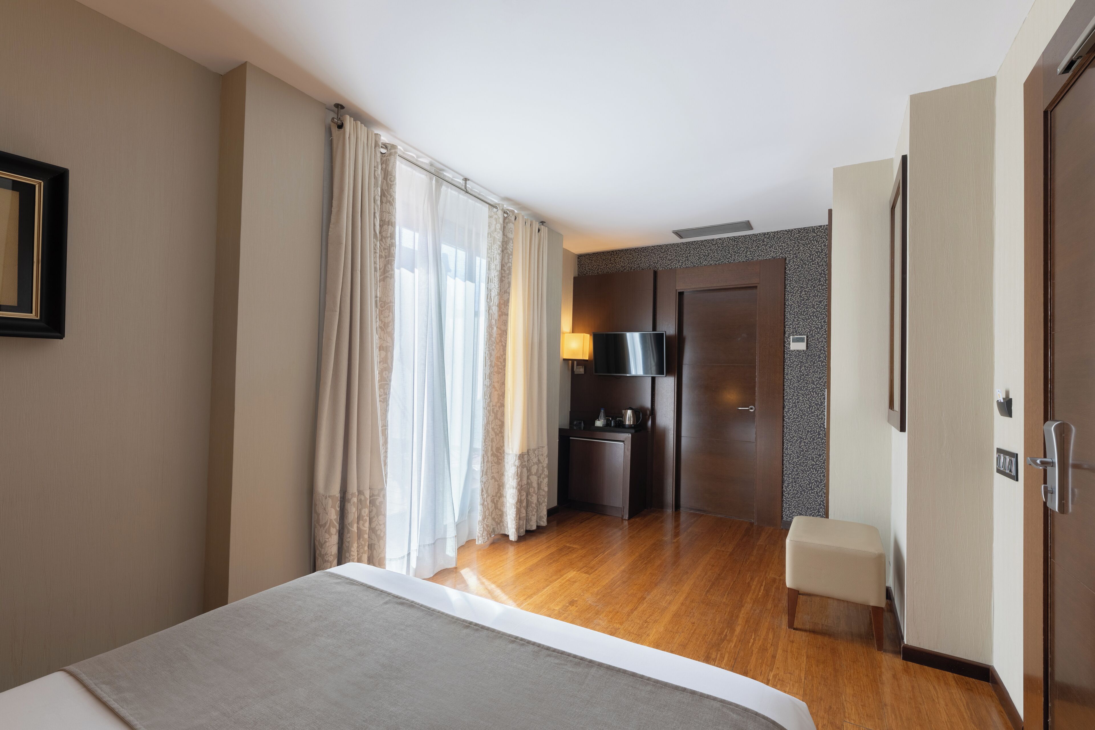 Una habitación de hotel con una cama, un escritorio pequeño con una lámpara, un televisor y un armario.